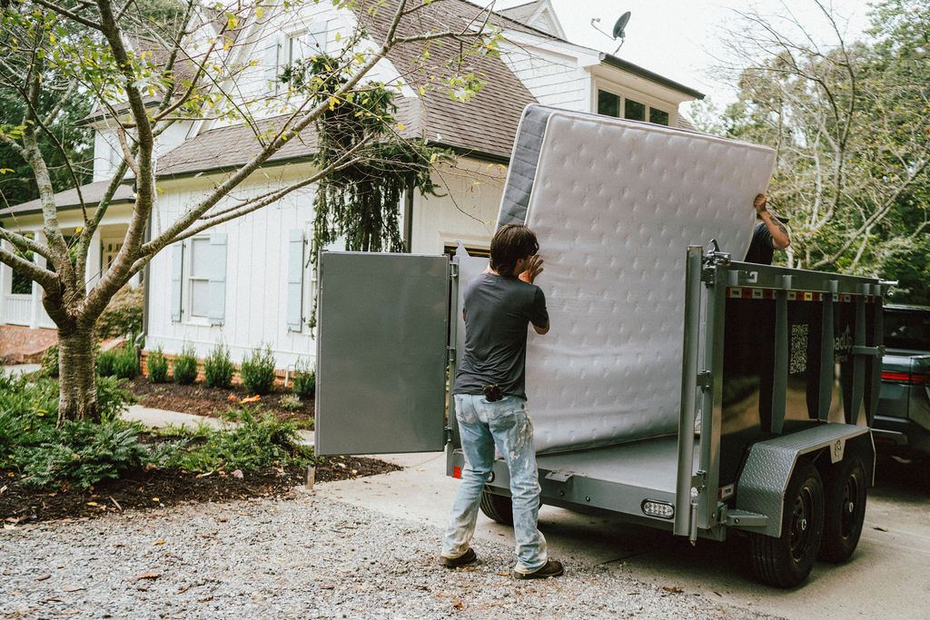 A Loader loading an old mattress into a LoadUp trailer in a residential driveway