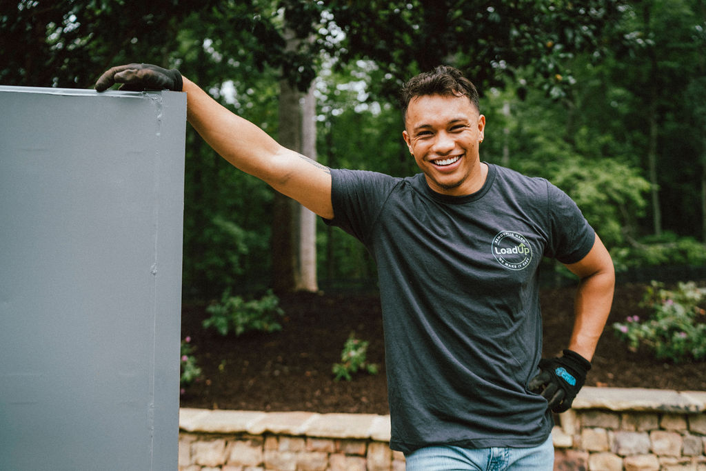 A JRP Loader in a LoadUp-branded shirt smiling on the job at a residential pickup