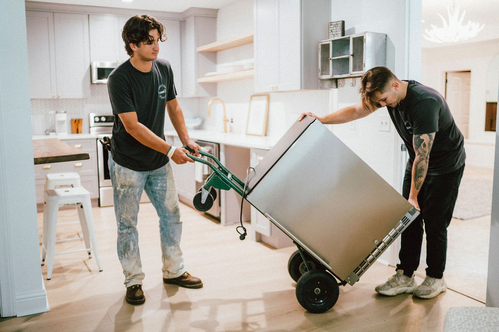 JRP Loaders moving a commercial refrigerator from a hospitality kitchen on a hand truck
